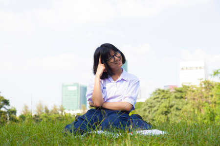 Girl sitting and smiling. On the lawn a happy and relaxation. On a clear sunny sky.の写真素材