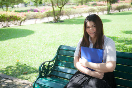 Student sit hold file. Sitting on a bench in the park.の写真素材