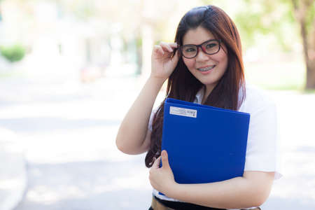 Student wearing glasses, smiling, holding a binder. Student was smiling and holding a file.の写真素材