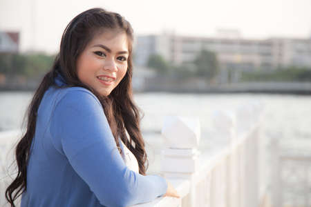 portrait smile woman stand near river at evening. relax in holiday long week.の写真素材