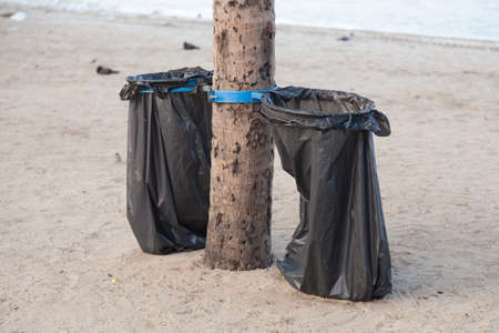 Black garbage bags. Plastic black trash on the beach under the coconut trees.の写真素材