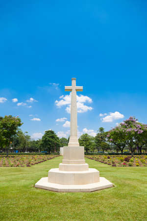 Cross in the cemetery Behind the sky is overcast. Cemetery with grass and trees.の写真素材