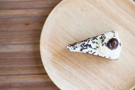 Chocolate cake, put it on a plate placed on a wooden table made from wood as well.の写真素材