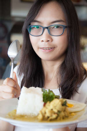 asia woman hold thai food.woman wear eyeglasses. relax and smile wear eyeglasses and hold spoon.の写真素材
