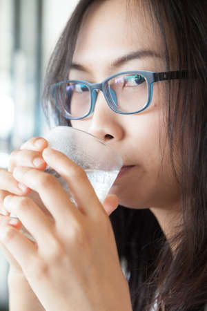 Asia woman drink water.smile woman dring water.woman wear eyeglasses smile and relax.の写真素材