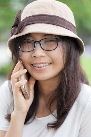 asia woman talk phone and smile.woman wear hat and eyeglasses.の写真素材