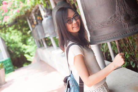 asia woman hit bell.joy and smile travel temple thailand.woman wear eyeglasses.の写真素材