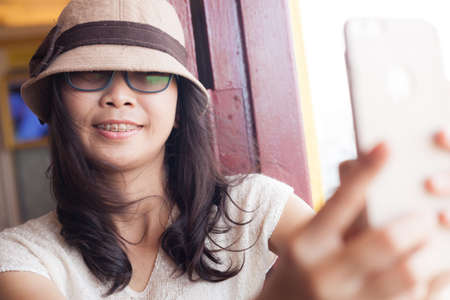 Beautiful young woman taking selfie.asia woman taking selfie wear hat and eyeglasses.の写真素材