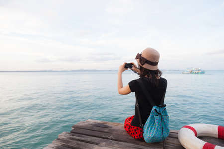 Woman photographing sea Sitting on a wooden bridge by the sea. A quiet seaの写真素材