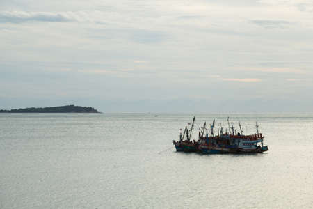 Fishing boats in sea In the morning calm ocean waves. And the sky started to morningの写真素材