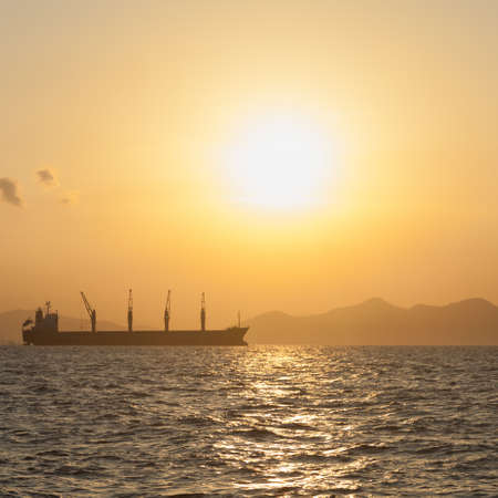 Large cargo ship In the morning the sun rises Ship moored in the seaの写真素材