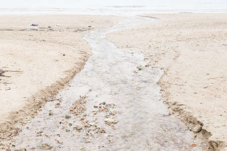 water flowing from the beach into the sea. The discharge of sewage dumped into the sea as a marine pollutant.の写真素材