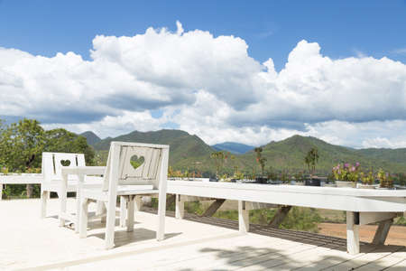 White tables and chairs on the balcony. The rear view of the mountains and the sky.の写真素材