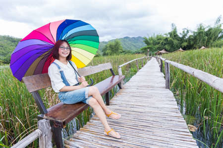 Woman sitting on an umbrella holding a bridgeの写真素材