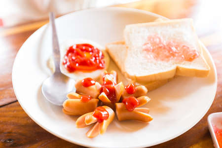 Sausage and bread with fresh strawberry jam for first meal of the dayの写真素材