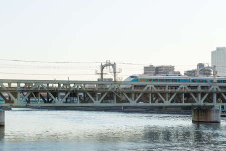 train on the bridge is crossing the river. In Tokyo city at daytime.
