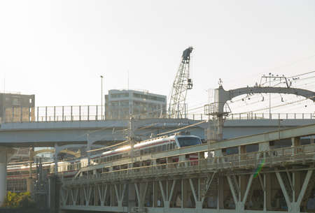 train on the bridge is crossing the river. In Tokyo city at daytime.