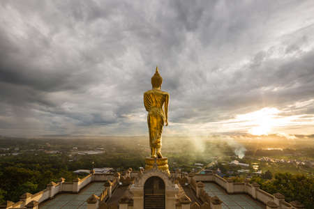 The Buddha is on top of the city. In the morning there are clouds and sunrise in front of the Buddha.の写真素材