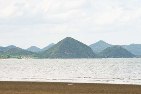 mountains near the sea. There are trees covering the mountains. And in front of the sea