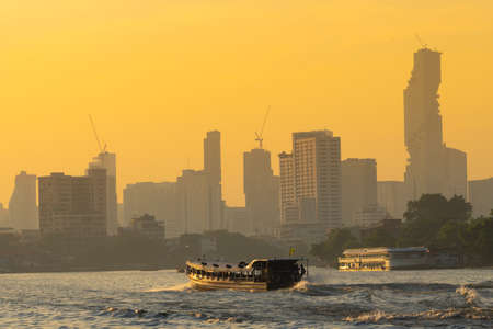 Boat traffic river in evening. Bangkok city and building skyscraper background in sunset.