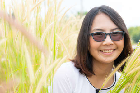 Asian woman relax in grass field. Smile and happy holiday in evening.の写真素材