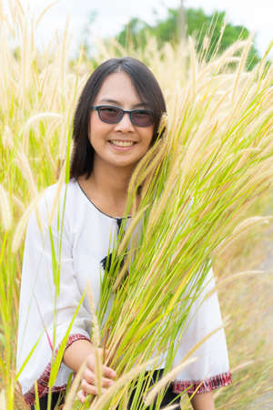 Asian woman relax in grass field. Smile and happy holiday in evening.の写真素材
