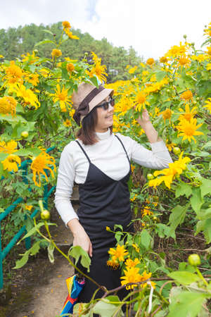 Asian woman traveler in holiday. Relax and happy in yellow flower field.の写真素材