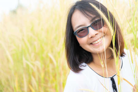 Asian woman relax in grass field. Smile and happy holiday in evening.の写真素材