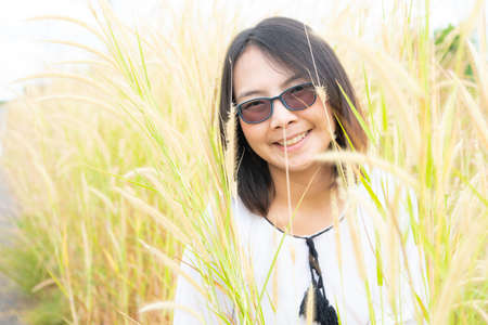 Asian woman relax in grass field. Smile and happy holiday in evening.の写真素材