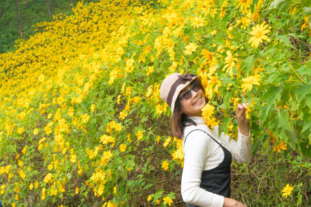 Asian woman traveler in holiday. Relax and happy in yellow flower field.の写真素材