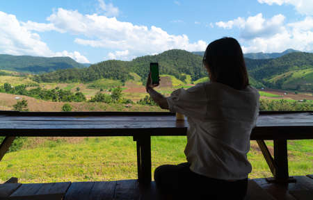 Silhouette woman using smart phone. Background mountain and forest in summer season.