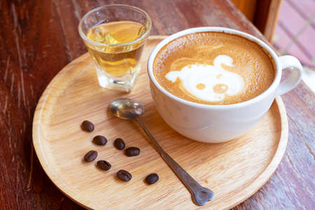 Latte art in a white glass On the wooden table in the cafeの写真素材