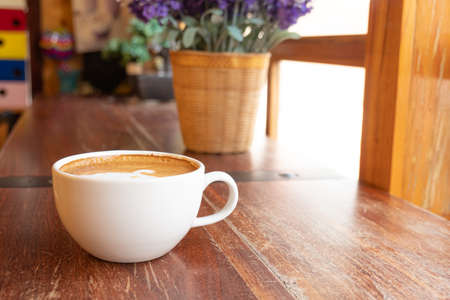 Latte art in a white glass On the wooden table in the cafeの写真素材