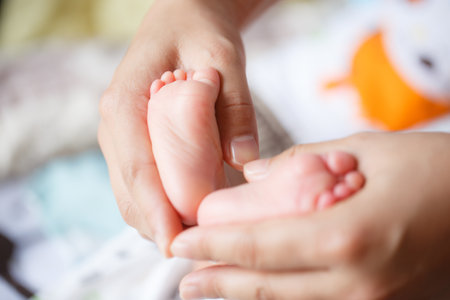 A gentle touch cradles tiny baby feet, symbolizing love and care in nurturing moment. This...
