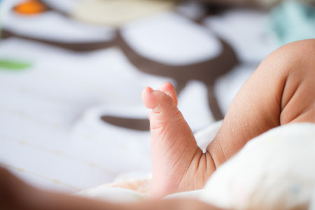 A close up of baby foot resting on soft surface, showcasing tiny toes and delicate skin. background features playful design, adding warm and cozy atmosphereの写真素材