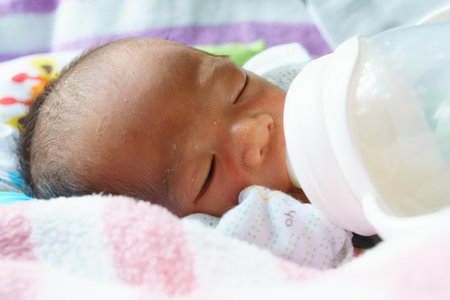 A peaceful baby drinking from bottle, wrapped in soft blanket, showcasing innocence and comfort. serene expression captures moment of nurturing and careの写真素材