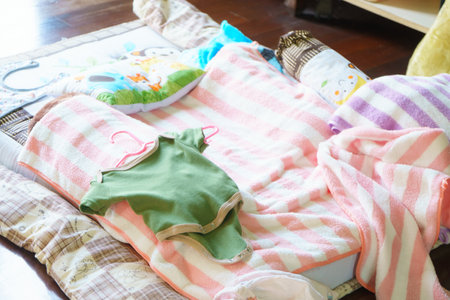 A Cozy baby bedding with colorful blankets and clothes on soft surface. scene evokes warmth and comfort, perfect for nursery or play areaの写真素材