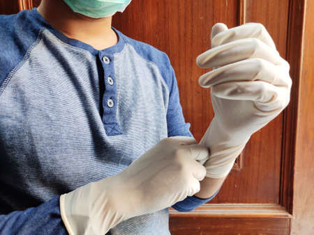 Man wearing hand gloves for Virus and flu protection at home, Covid 19 , SARS ,Corona, Selective focus.の写真素材