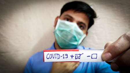 Covid corona virus patient test positive result man face wear face mask, selective focus , blurred background.の写真素材