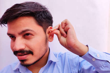 Man cleaning ear using ear swabs or cotton ear sticks on the light background. Ear care concept for Hygiene.の写真素材