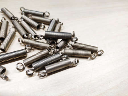 Metal spring mechanical Helical steel coil wire winding detail, Abstract pile of shiny compression and extension metal parts on black background. Springy machine components.の写真素材
