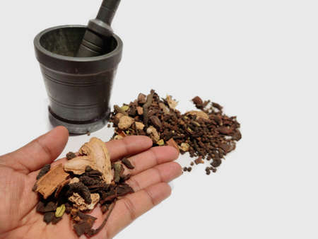Garam masala Mix spices and herbs on hand and in background with mortar on white background with space for text Selective focus.の写真素材