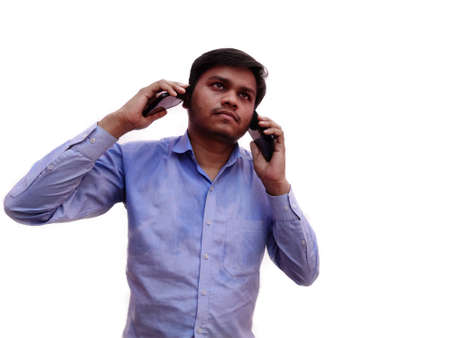 Young man talking on two mobile phone at a time ,he is too busy in business posing on white background.の写真素材