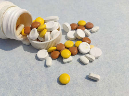 Bottle of pills on blue background for illness cure, Tablets spread on paper with space for textの写真素材