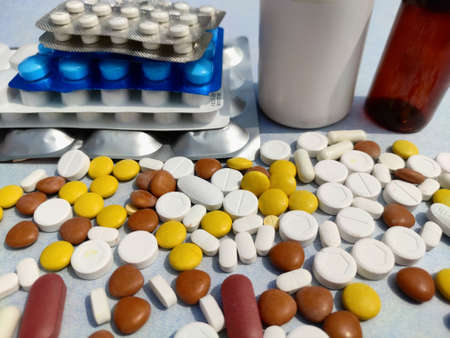Bottle of pills on blue background for illness cure, Tablets spread on paper with space for textの写真素材