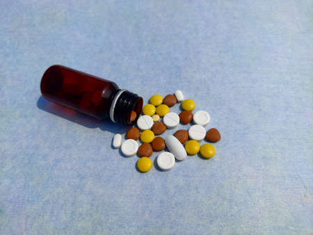 Bottle of pills on blue background for illness cure, Tablets spread on paper with space for text