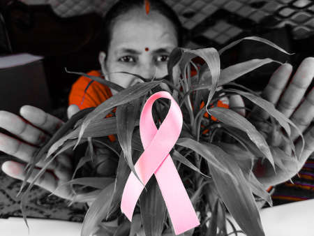 woman grab pink ribbon a cancer fighter , cover hands on cancer symbol.