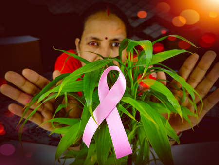 woman grab pink ribbon a cancer fighter , cover hands on cancer symbol.