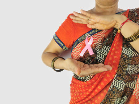 indian Woman in sari with pink ribbon covering by hands for awareness for breast cancer in October month.の写真素材