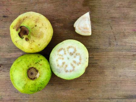 Guava amrud cut slices white pulp on wooden background with Space for text